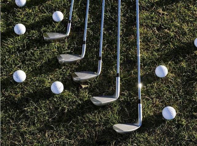 Golf clubs and balls laid out on grass